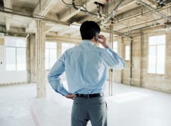 Businessman using mobile phone in empty office space, rear view